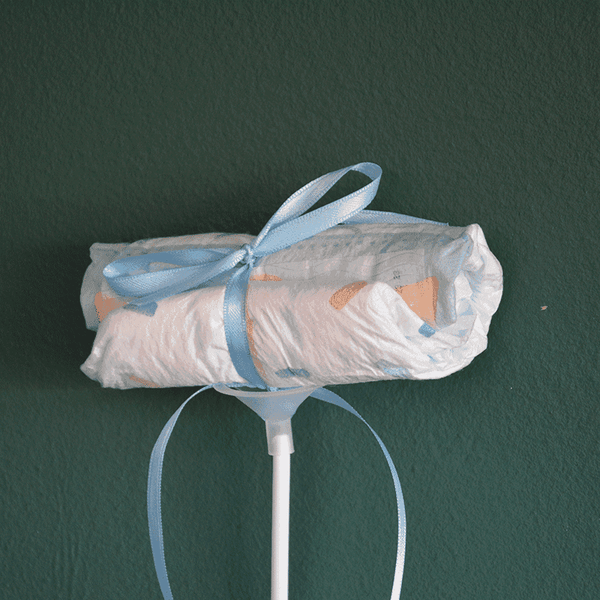Einzelner Windel Einstecker mit blauer Schleife auf Stab, liebevolles Detail für Baby-Blumensträuße und Geschenkideen zur Geburt.