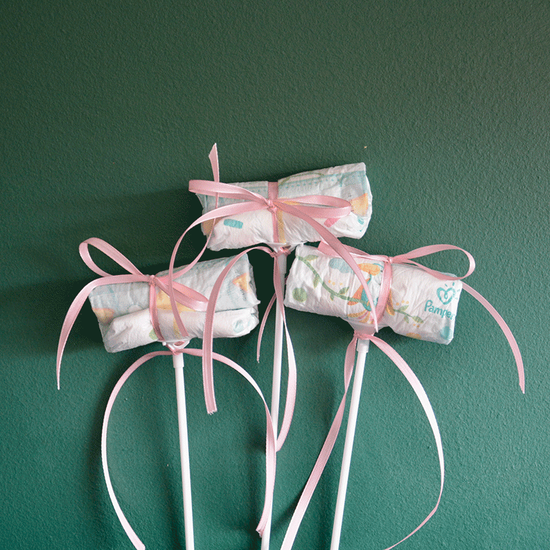Drei Windel Einstecker mit rosa Schleifen auf weißen Stäben, perfektes Add-on für Blumensträuße zur Geburt eines Mädchens.