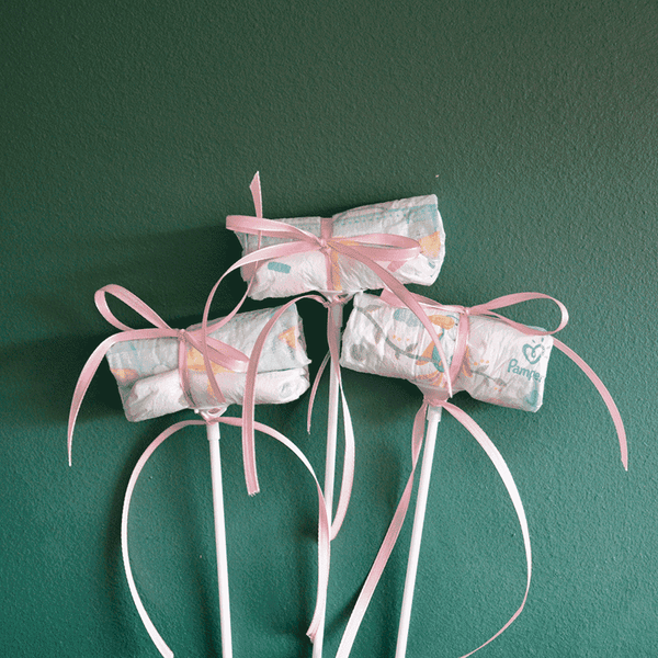 Drei Windel Einstecker mit rosa Schleifen auf weißen Stäben, perfektes Add-on für Blumensträuße zur Geburt eines Mädchens.