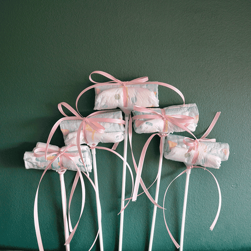 Fünf Windel Einstecker mit rosa Schleifen auf Stäben, dekoratives Accessoire für Baby It's a Girl Blumenversand zur Geburt.